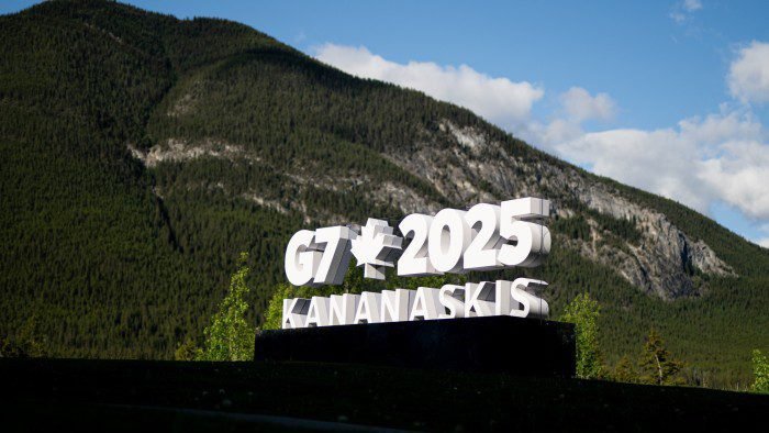 A large white sign reads ‘G7 2025 Kananaskis’ with a maple leaf symbol, set against a backdrop of forested mountains