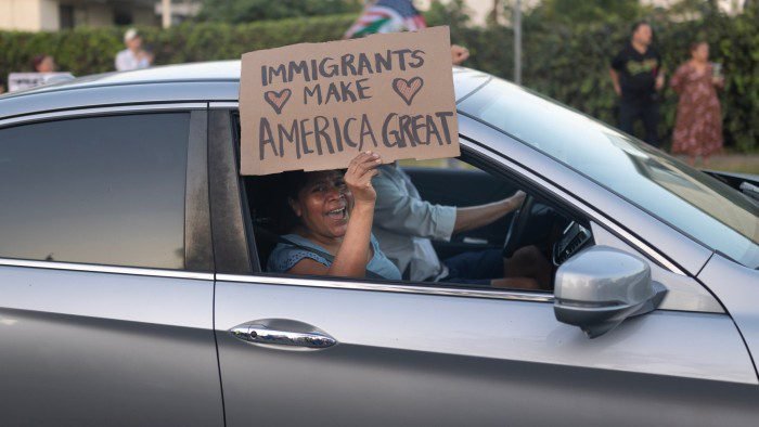 A woman holds a placard that says ‘Immigrants make America great’