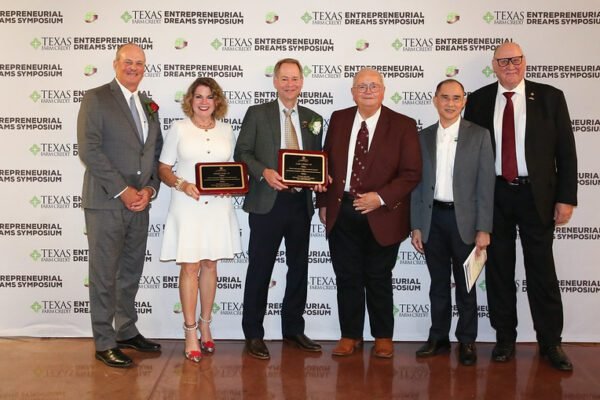 Former students inducted into Tyrus R. Timm Honor Registry Six individuals standing, two of them holding awards, in from of a white backdrop that says Texas Farm Credit Entrepreneurial Dreams Symposium